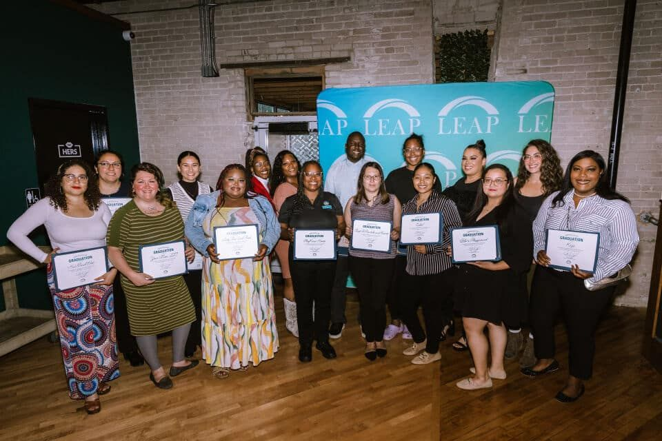 Members from the one and all program stand one row behind the other holding their certificates. Lissy stands on the left
